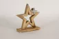 Preview: Eleganter Holzstern verziert mit Metallstern – moderne Weihnachtsdeko auf dem Tisch