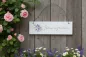Preview: Deko-Schild Traumgarten aus Holz, rechteckig, aufgehängt an einem Gartenhäuschen, mit Pflanzen und Blumen im Hintergrund für eine idyllische Gartendekoration