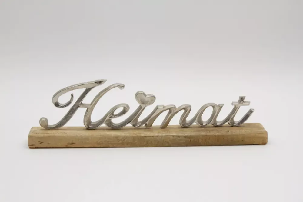 Freistehender Schriftzug Heimat aus silbernem Metall auf Regal